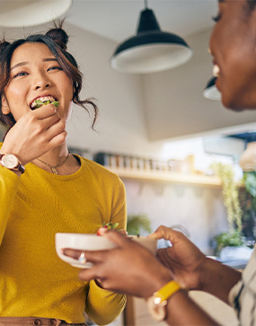 Group of friends eating meal together in kitchen
